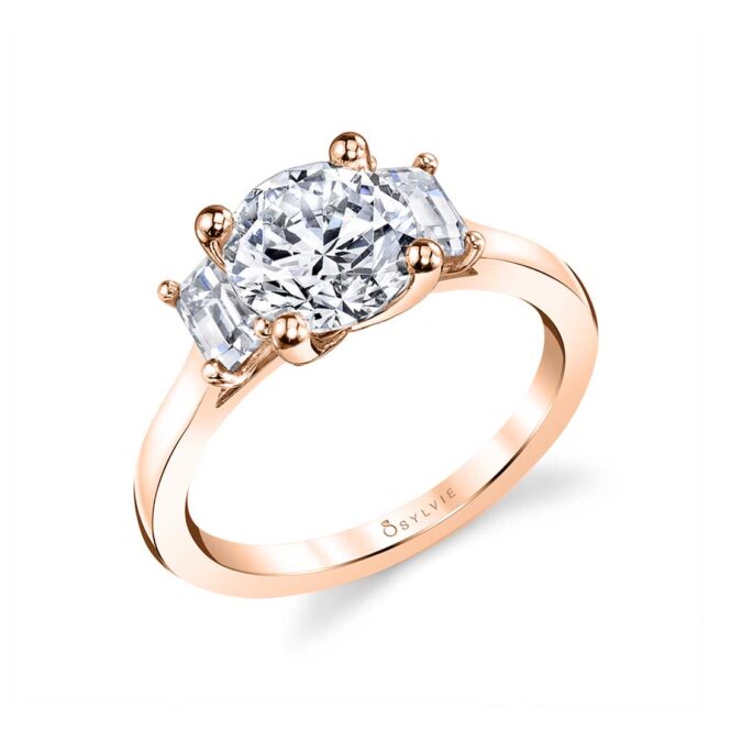 three stone engagement ring with emerald cut side stones in rose gold