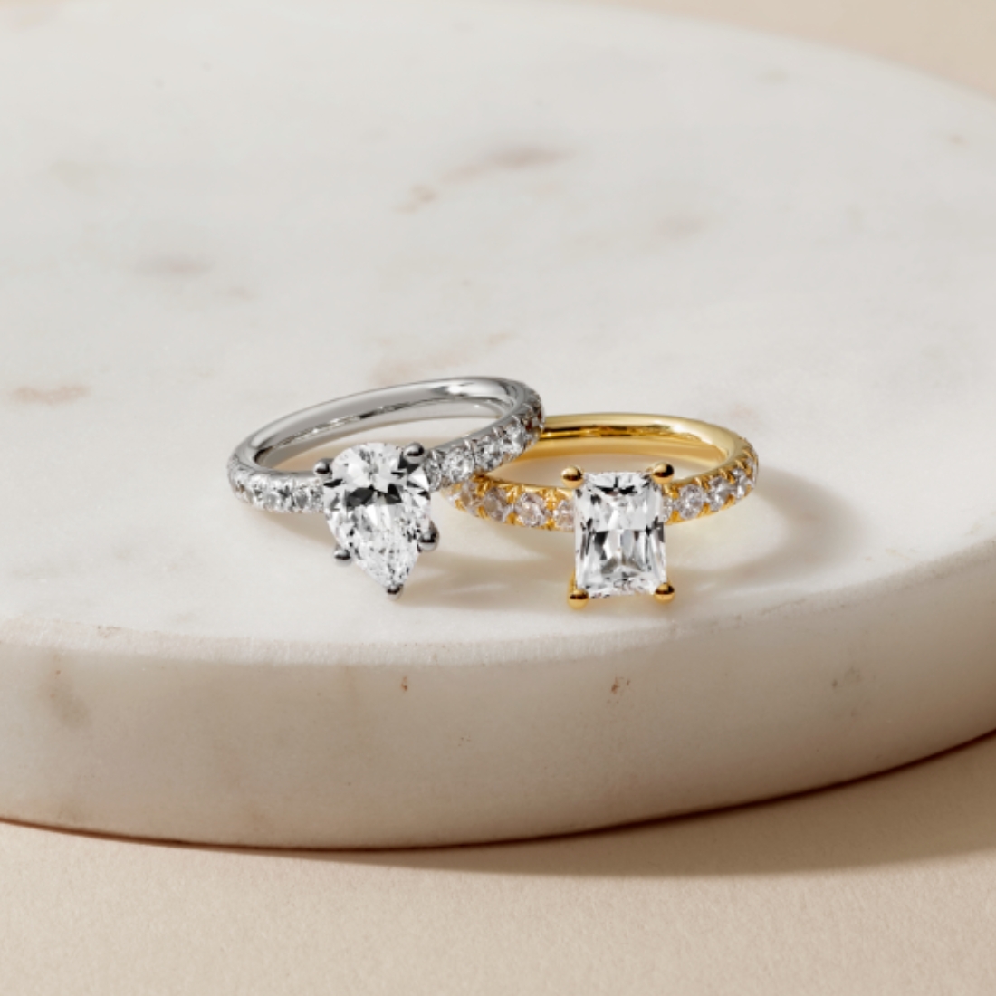 a white gold and yellow gold classic engagement ring sitting on a white marble platform